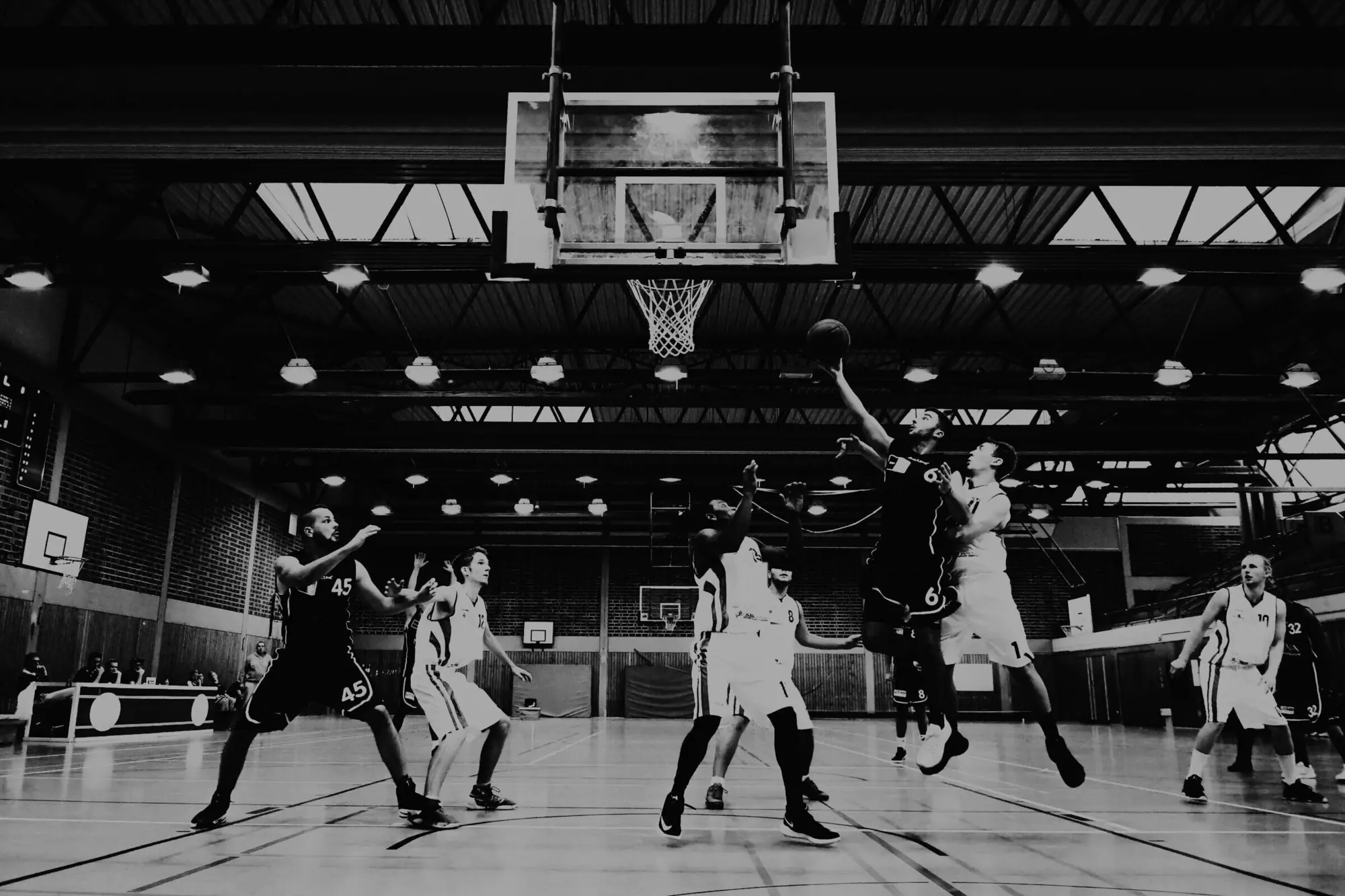 Players going for a rebound in a league game in a local sports hall.